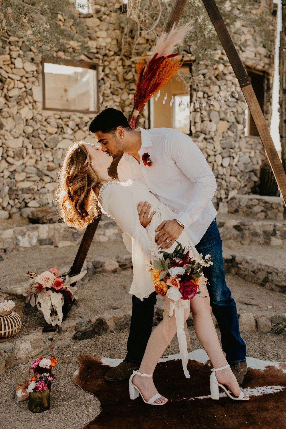 a man and woman kissing in front of a stone building