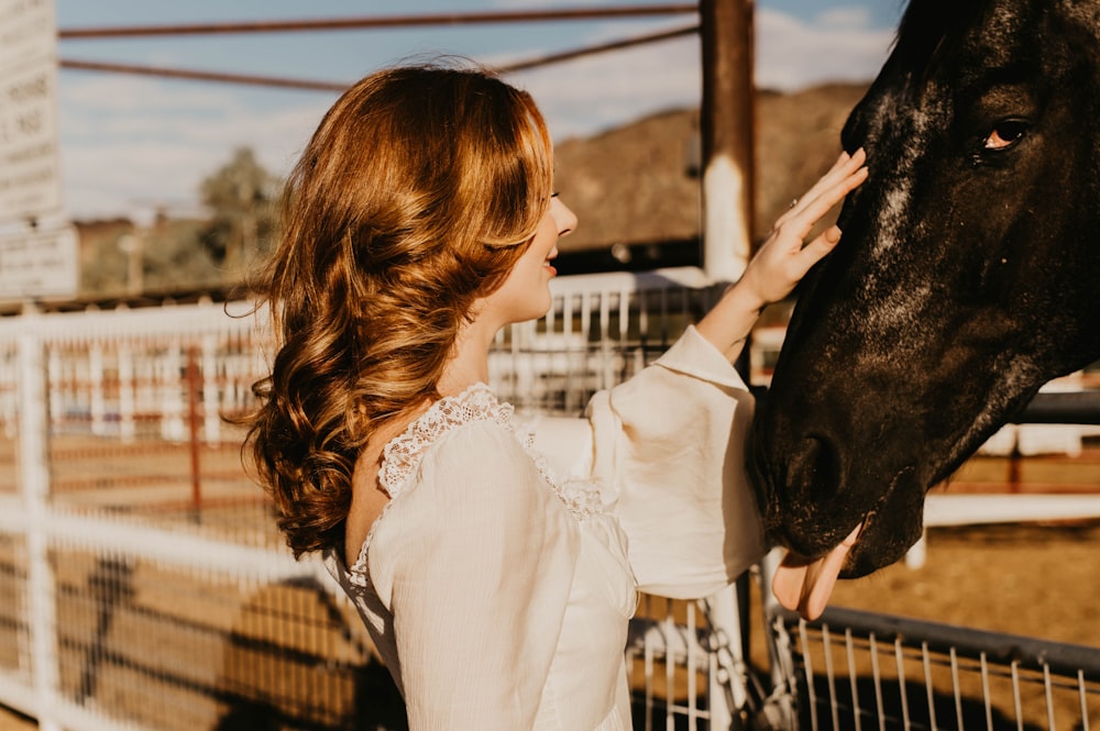 a woman is petting a horse in a corral