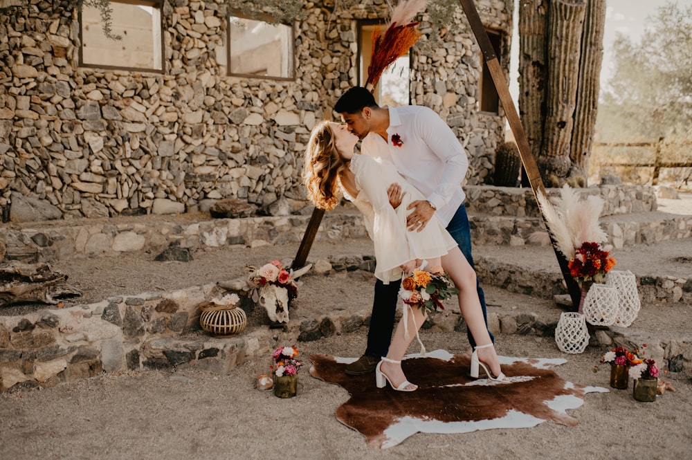 Ein Mann und eine Frau, die sich vor einem Steingebäude küssen
