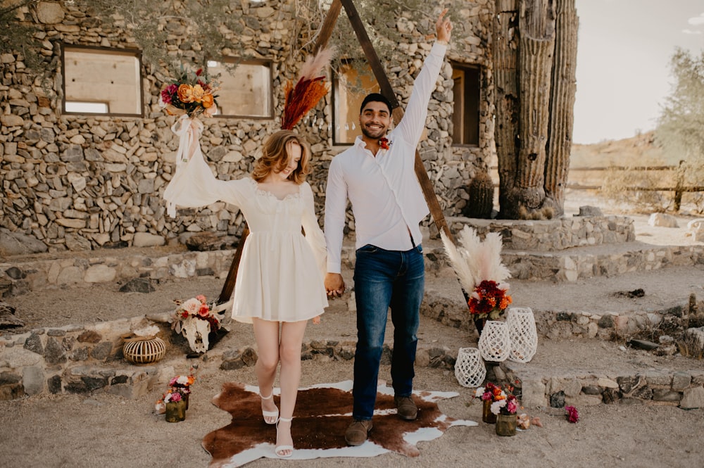 a man and a woman holding hands in front of a stone building