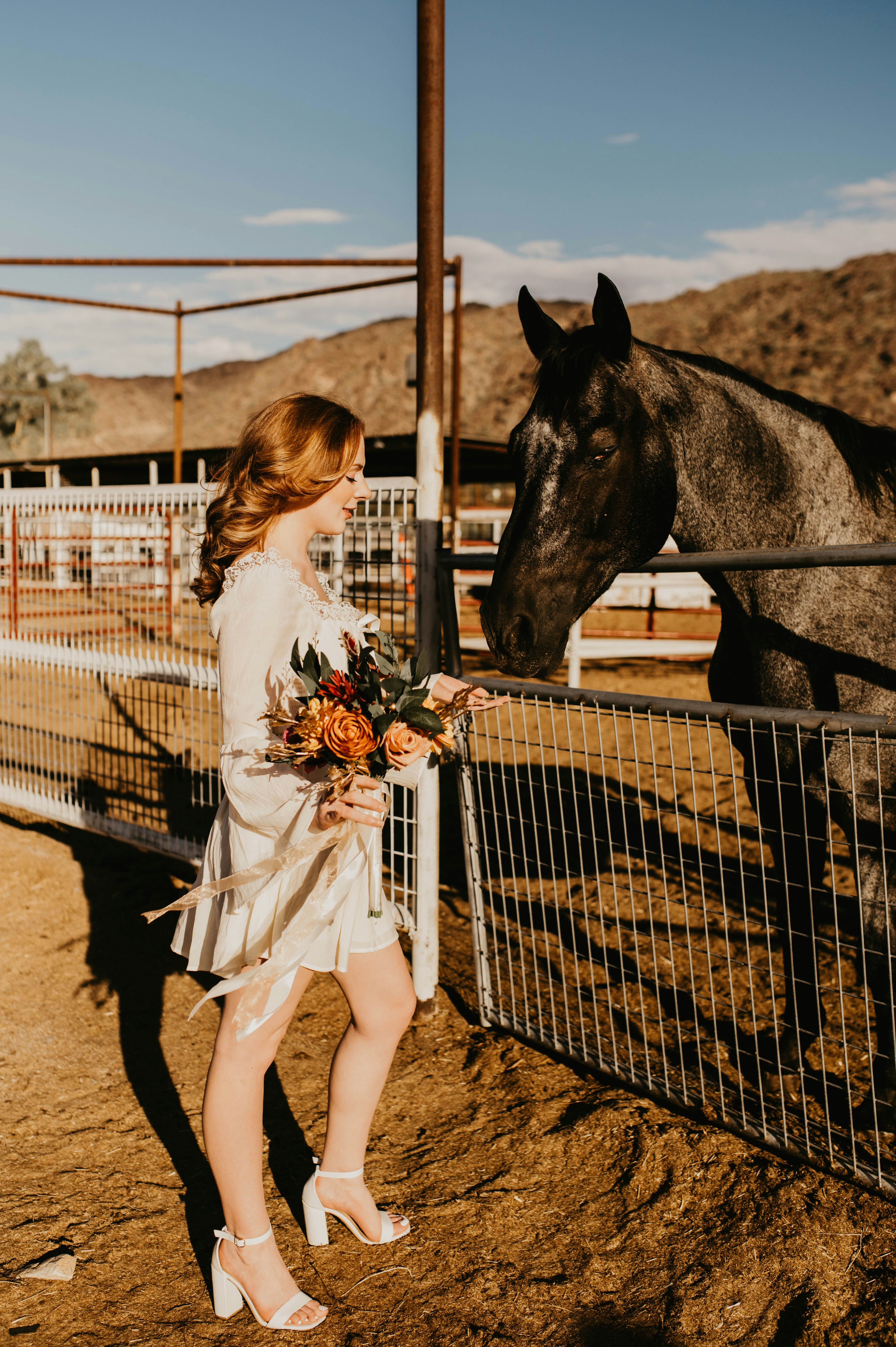 a woman standing next to a horse near a fence