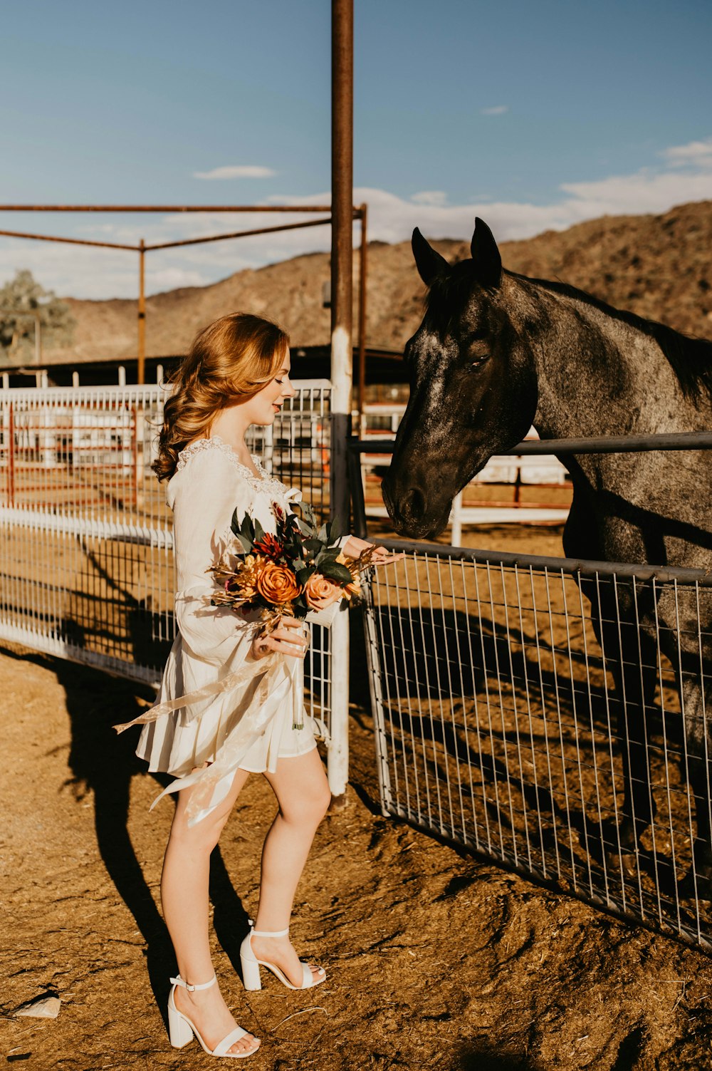 a woman standing next to a horse near a fence