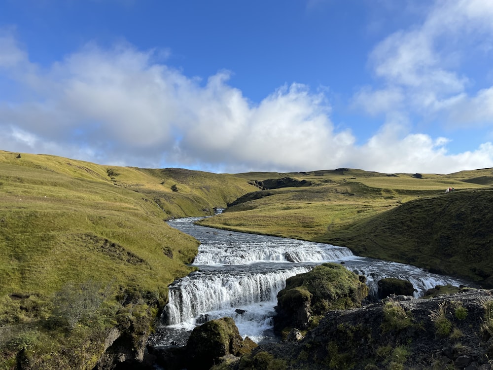 a river running through a lush green hillside