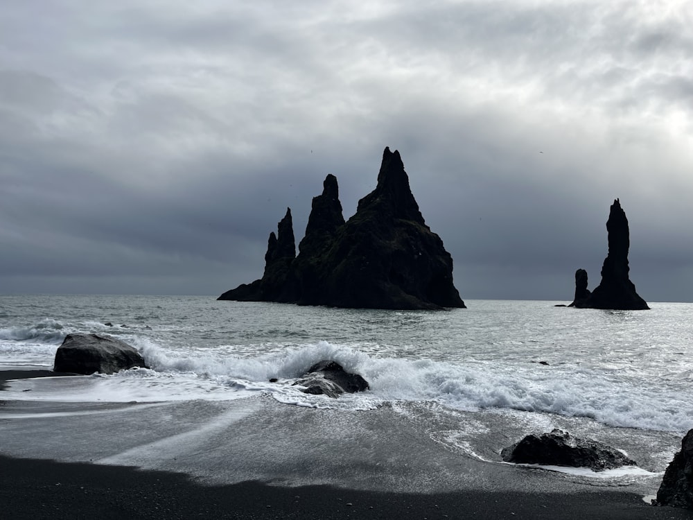 a group of rocks sitting on top of a beach next to the ocean