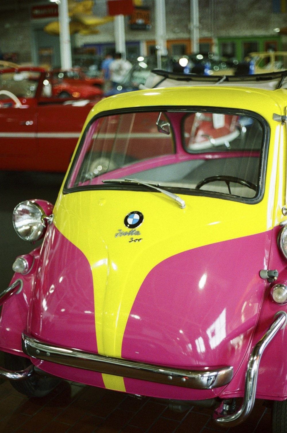 a pink and yellow car parked in a garage