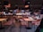 A modern cafeteria with neatly organized rows of tables and chairs, featuring a prominent illuminated sign that says 'LOVE AT FIRST BITE.' The seating area consists of light wooden tables and chairs with a mesh design. The ambiance is enhanced by pendant lights hanging from the ceiling, and there are large screens displaying images in the background.