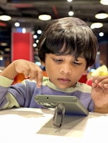A child happily coding on a tablet in a bright room.