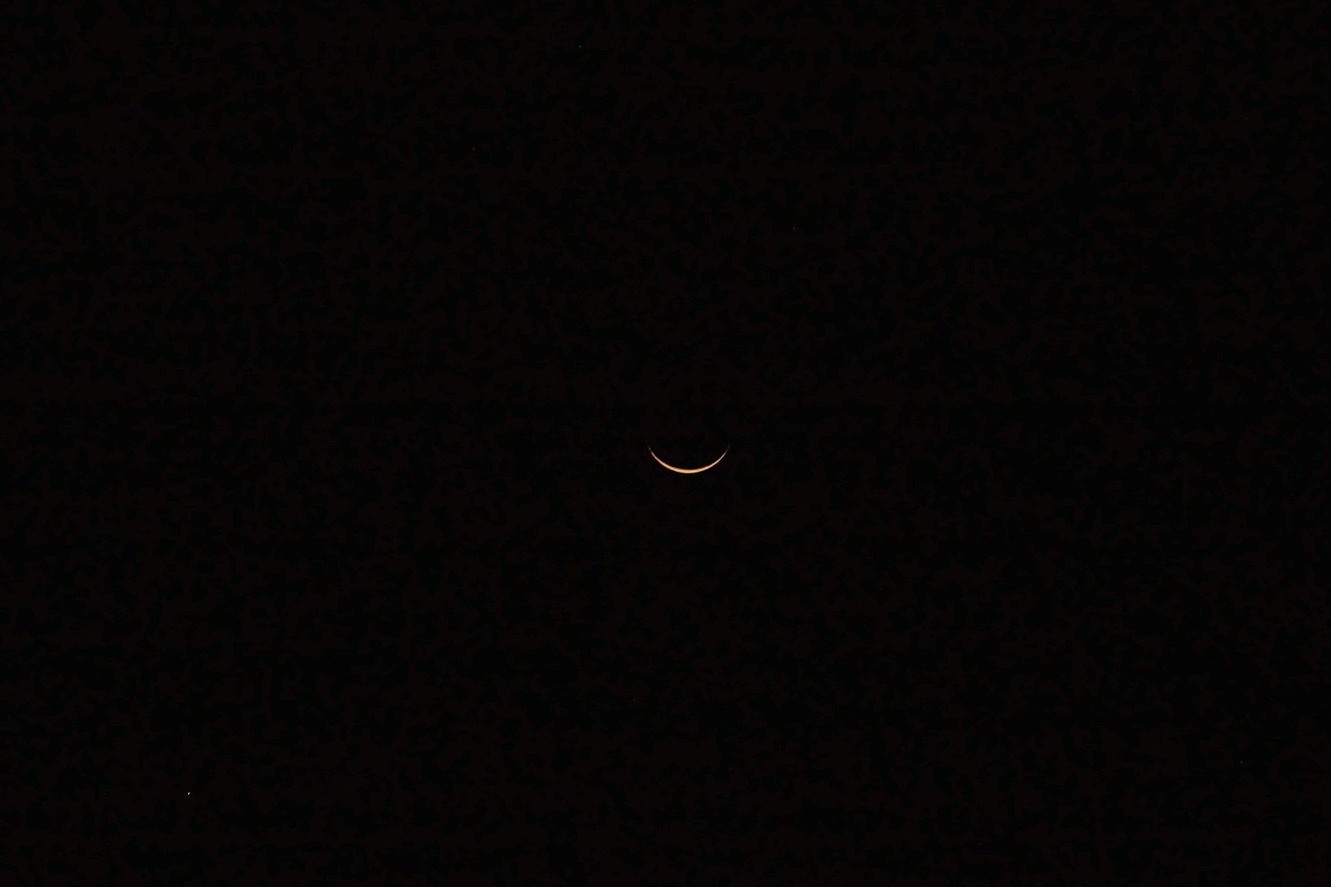 A minimalist logo of a crescent moon with a light burst in the center, illuminated gently on a misty, dark backdrop.
