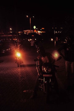 Night shot of a motorcycle rally with glowing headlights and city lights.