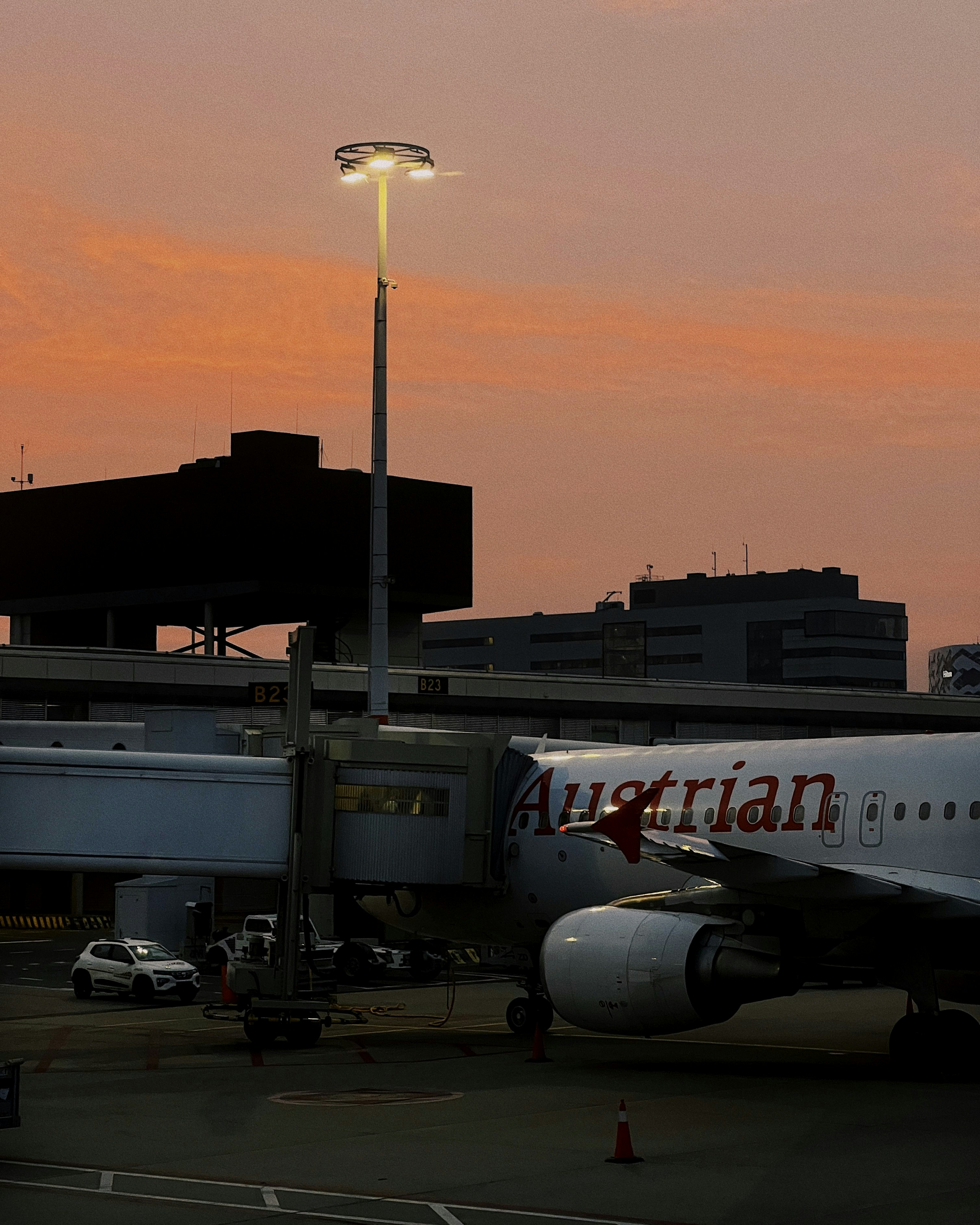 an airplane parked at an airport with a pink sky in the background