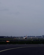 Construction workers installing lighting systems along an airport runway at dusk.