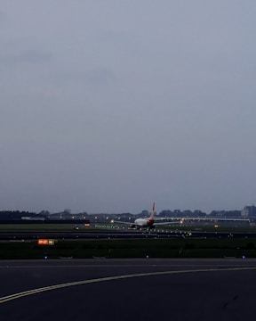 Construction workers installing lighting systems along an airport runway at dusk.
