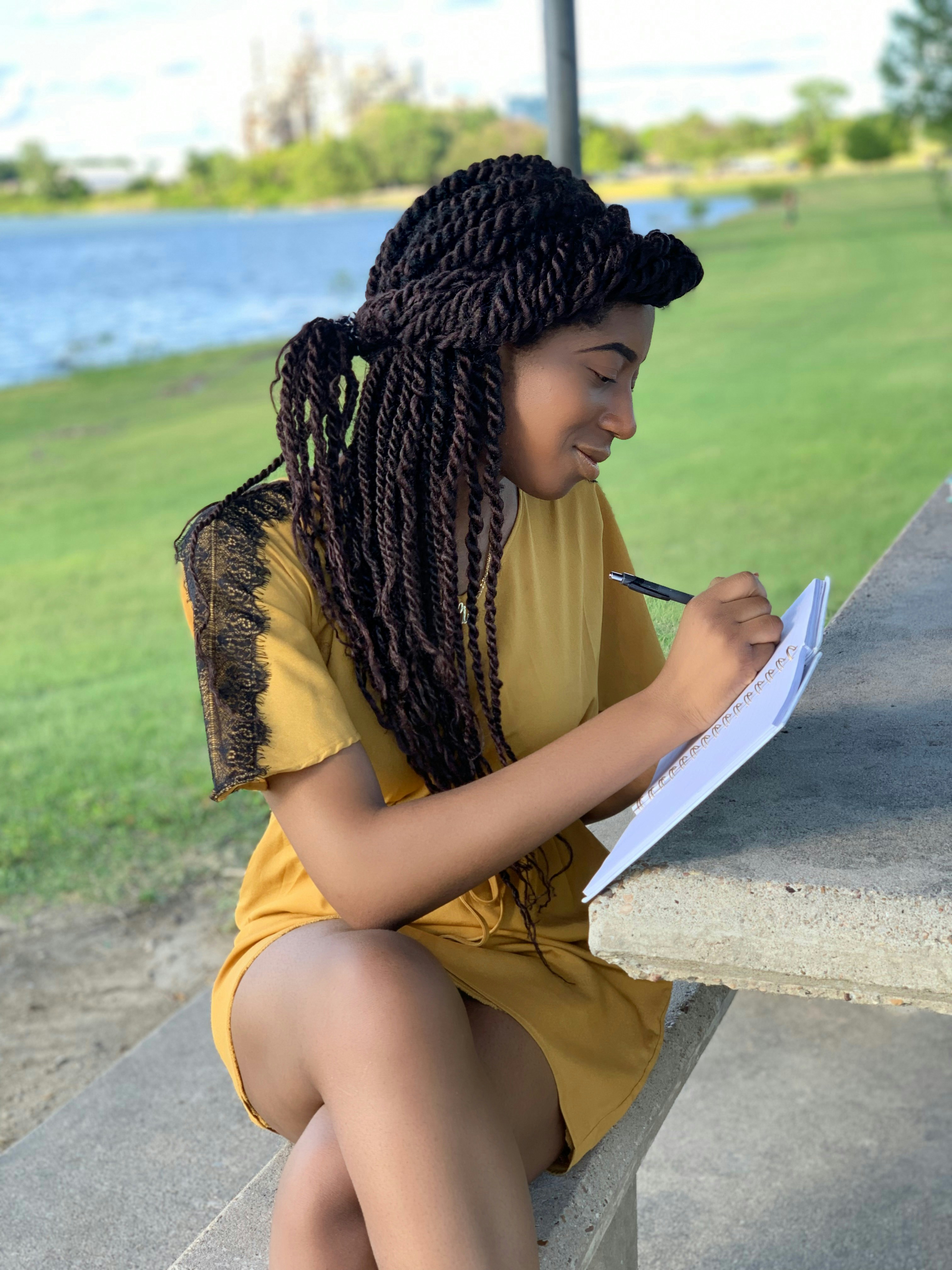A woman writing in a journal on a balcony with a scenic view.