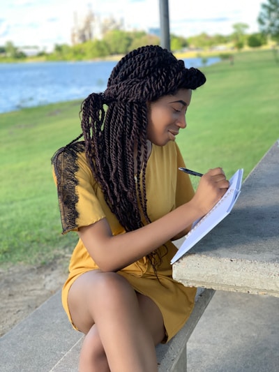 a woman sitting on a bench writing on a piece of paper