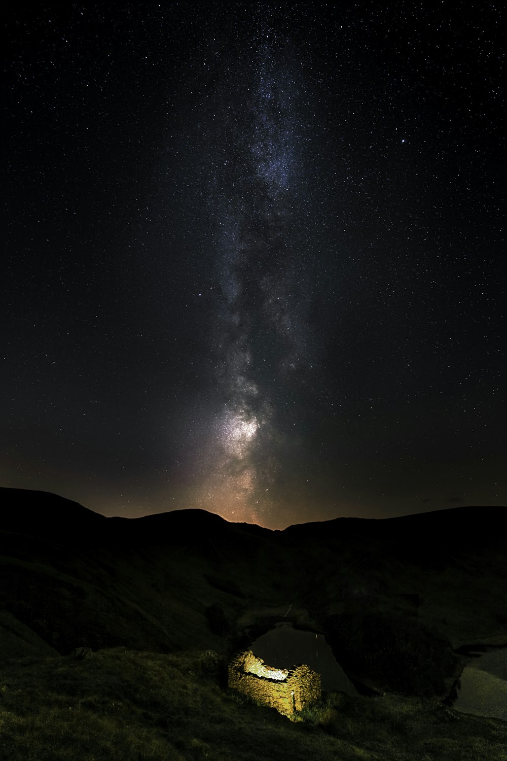 the night sky is filled with stars above a small hut