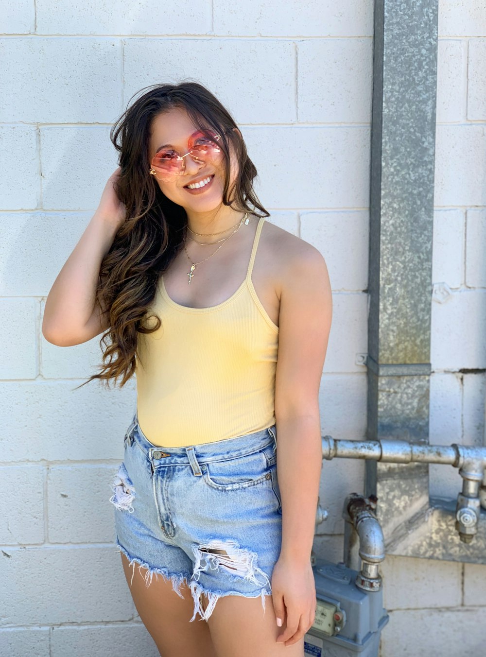 a woman wearing a yellow tank top and denim shorts