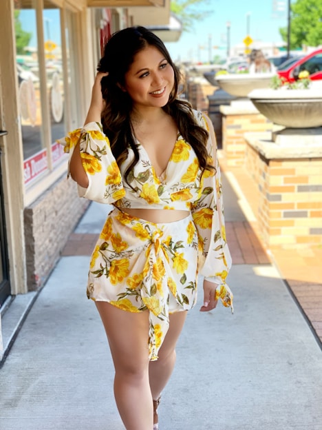 a woman is walking down the sidewalk in a yellow dress
