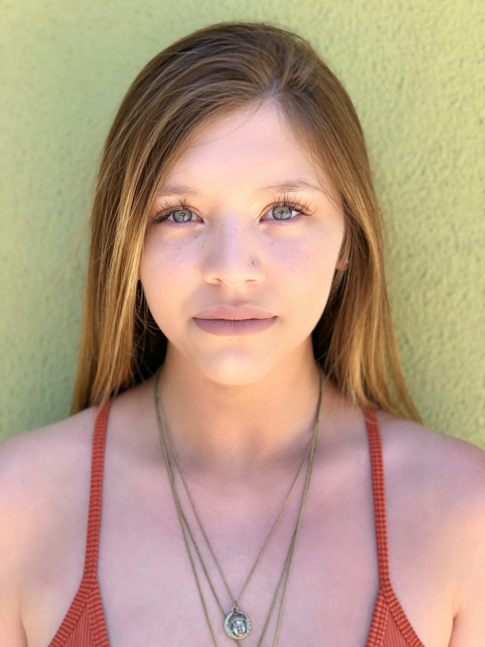 a woman wearing a red tank top and a necklace