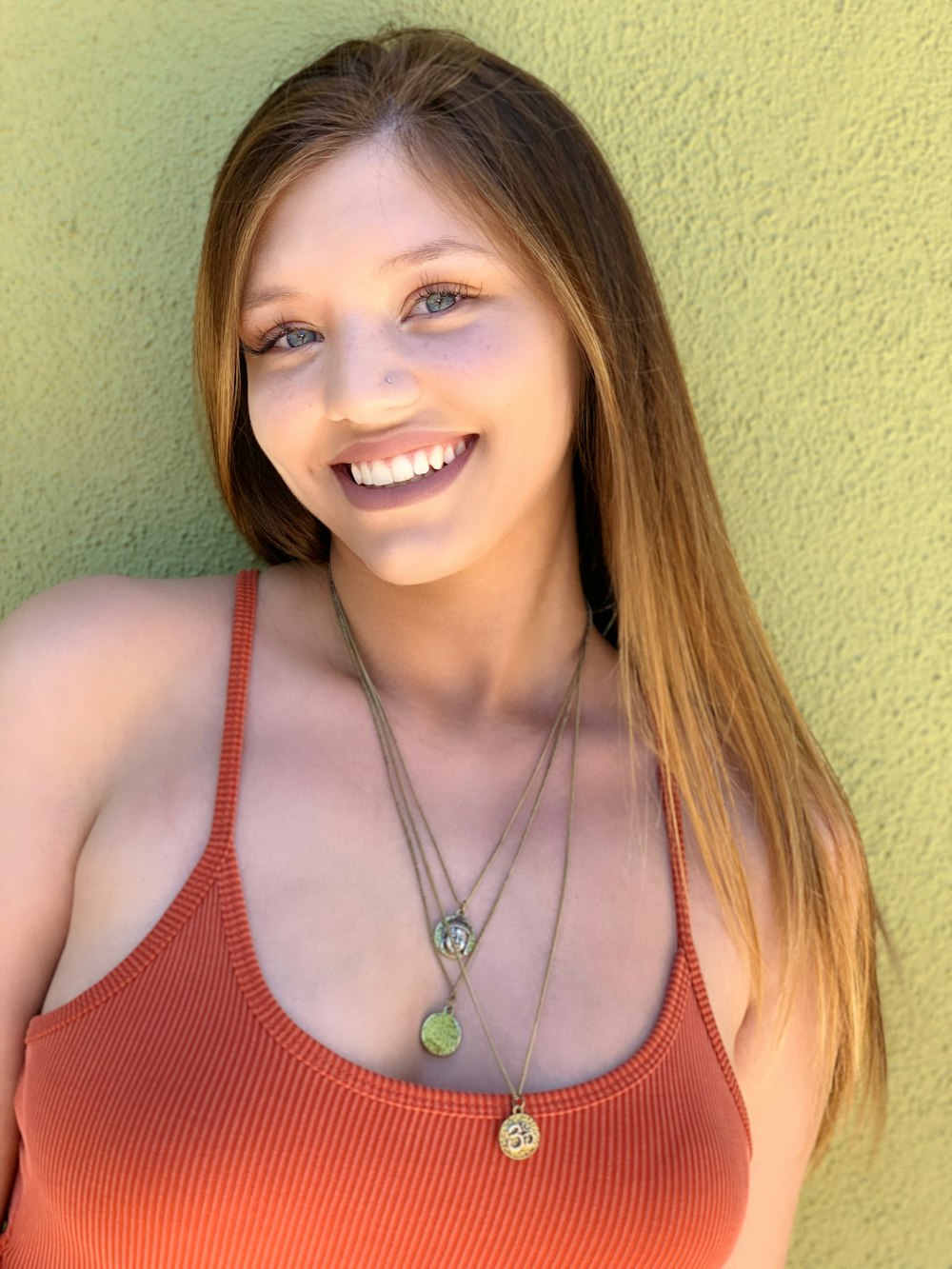 a woman in an orange tank top posing for a picture