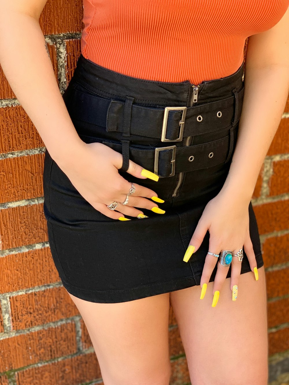 a woman with yellow nails and a black skirt