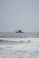 A fisherman hauling his catch aboard while waves gently break over the boat’s edge.