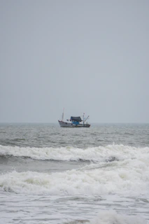 A fisherman hauling his catch aboard while waves gently break over the boat’s edge.