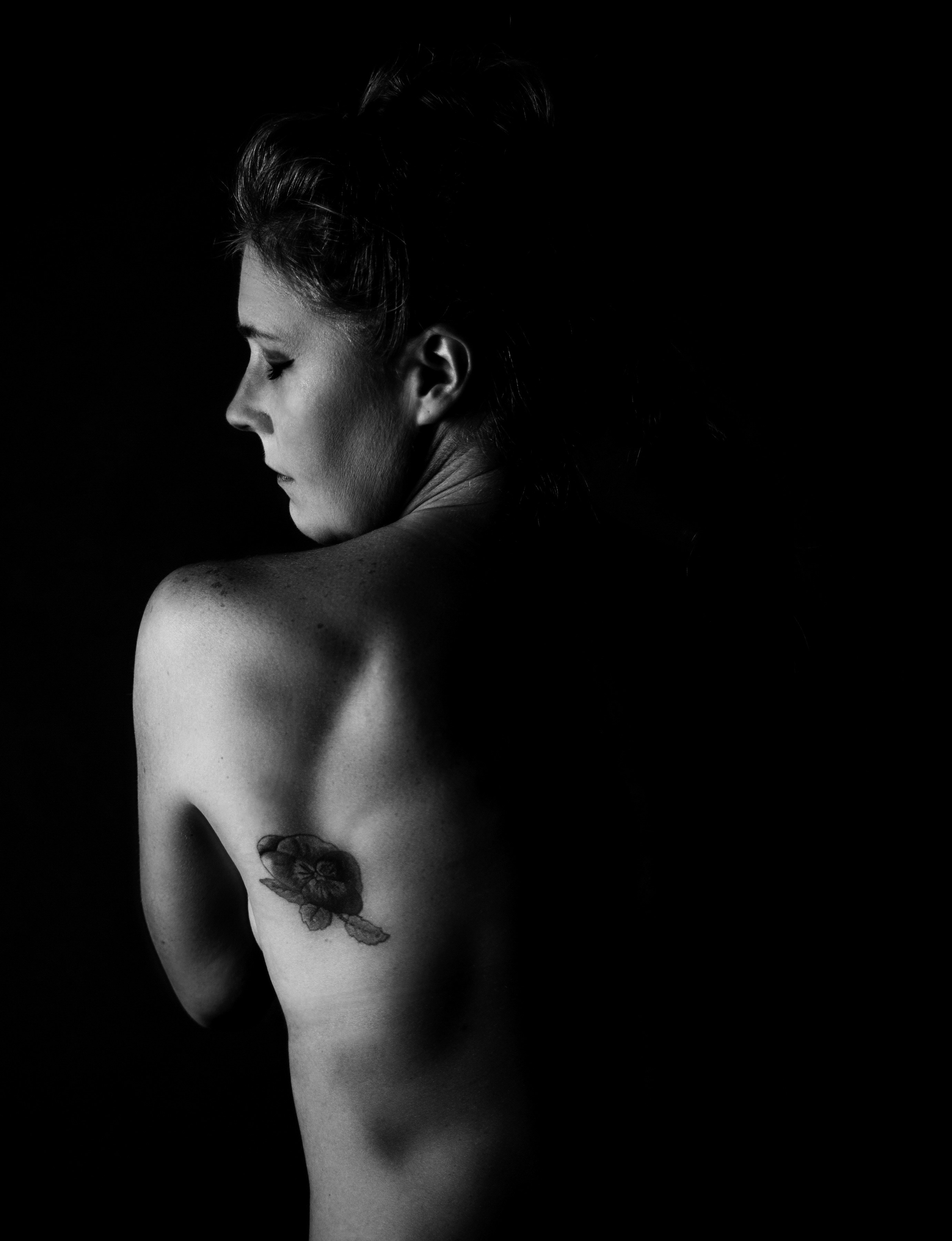 Alternative fashion model in dark space-themed clothing, moody studio lighting, tattoo art visible on skin