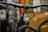 A close-up view of a bicycle's handlebar and front frame, with the brand name 'Gradient' visible on the handlebar. The frame has a logo with mountains and raindrop designs. Water droplets are seen on the handlebars and frame, indicating a wet or rainy environment. The background is blurred with various colors, suggesting an indoor setting or store.
