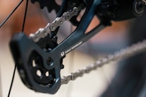 A close-up view of a bicycle drivetrain featuring a chain and rear derailleur with the words 'Eagle Technology' visible on the component. The focus is on the intricate details of the chain and gear mechanism.