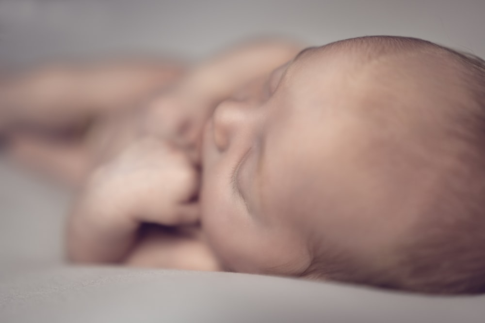 a close up of a baby sleeping on a bed