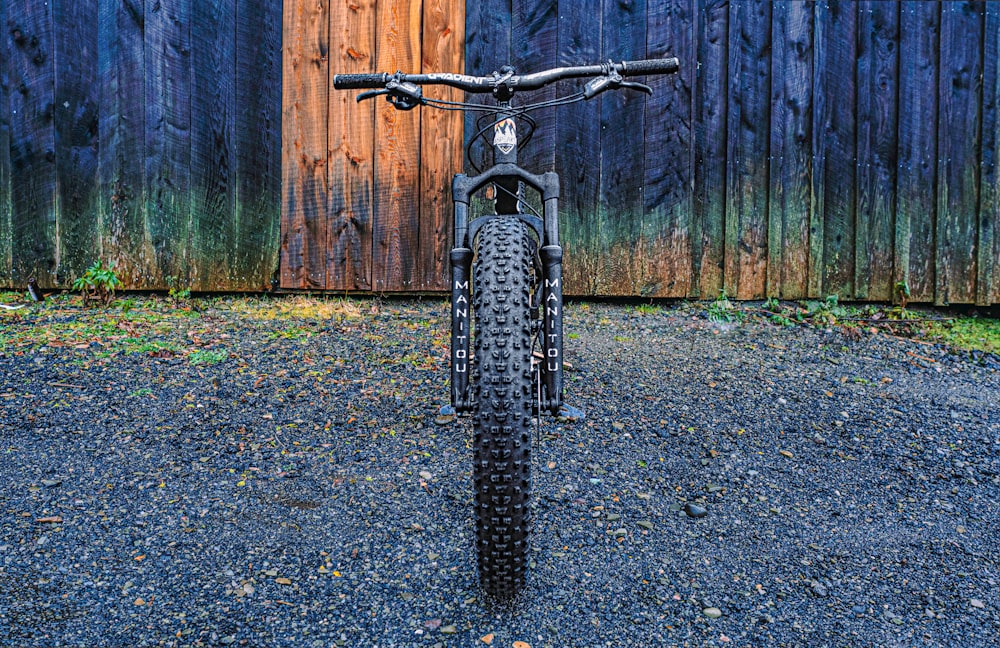 a bicycle parked in front of a wooden fence