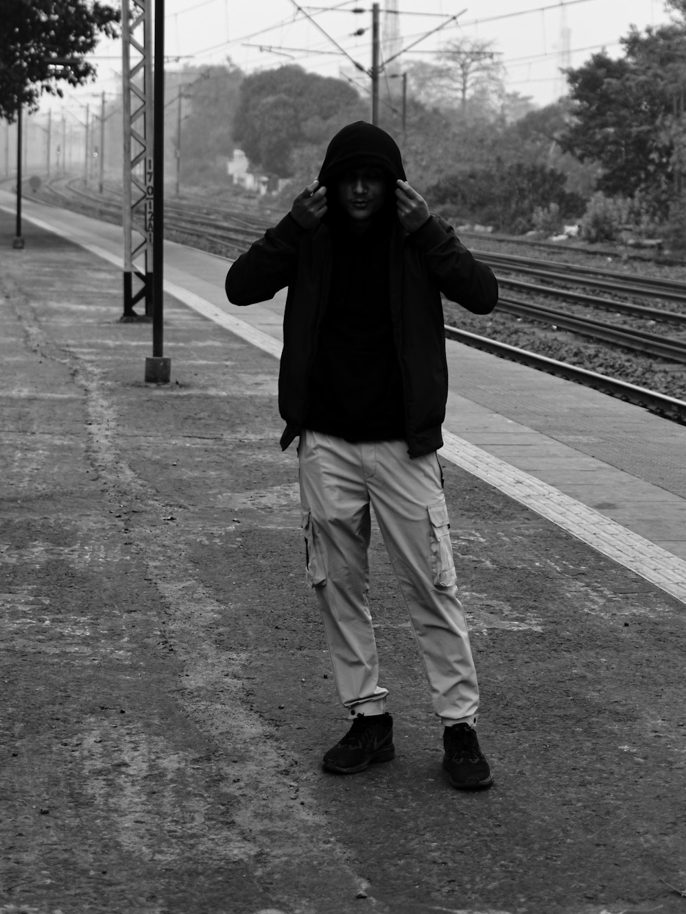a man in a hoodie standing on a train platform