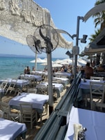 Guests enjoying sandwiches and toasts at shaded tables near the beach bar.