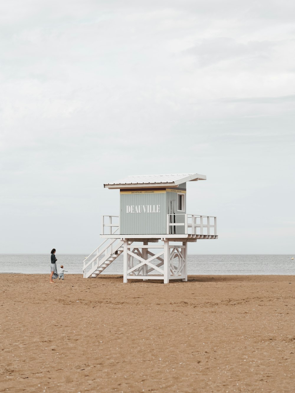 a lifeguard stand on the beach with a person walking towards it