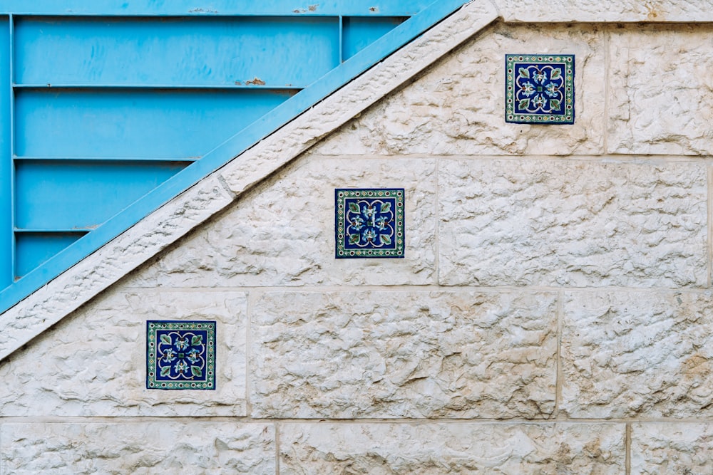 a blue stair case next to a stone wall