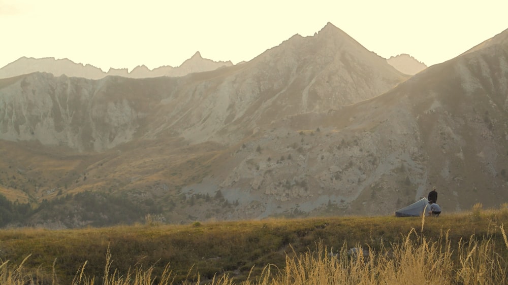 a person sitting in a field with mountains in the background