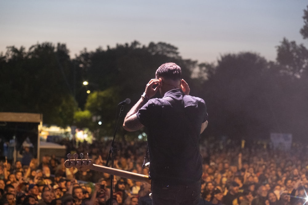 a man standing in front of a crowd holding a guitar