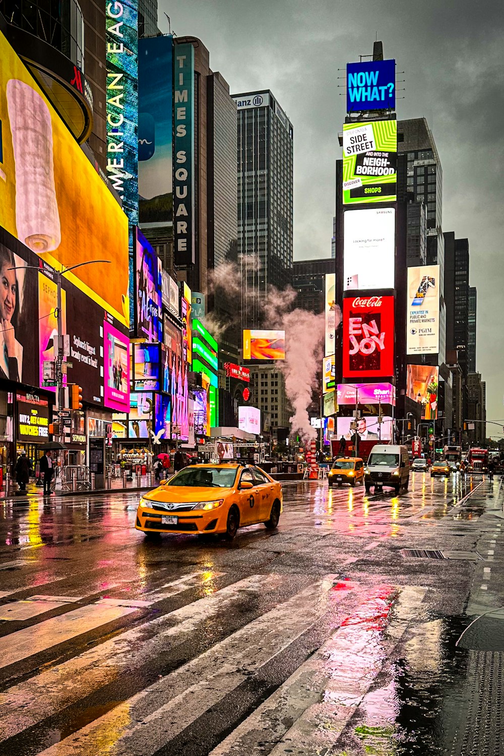 a yellow car driving down a street next to tall buildings