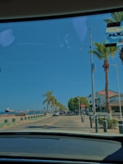 A Compass taxi cruising along a coastal road with palm trees swaying in the breeze.