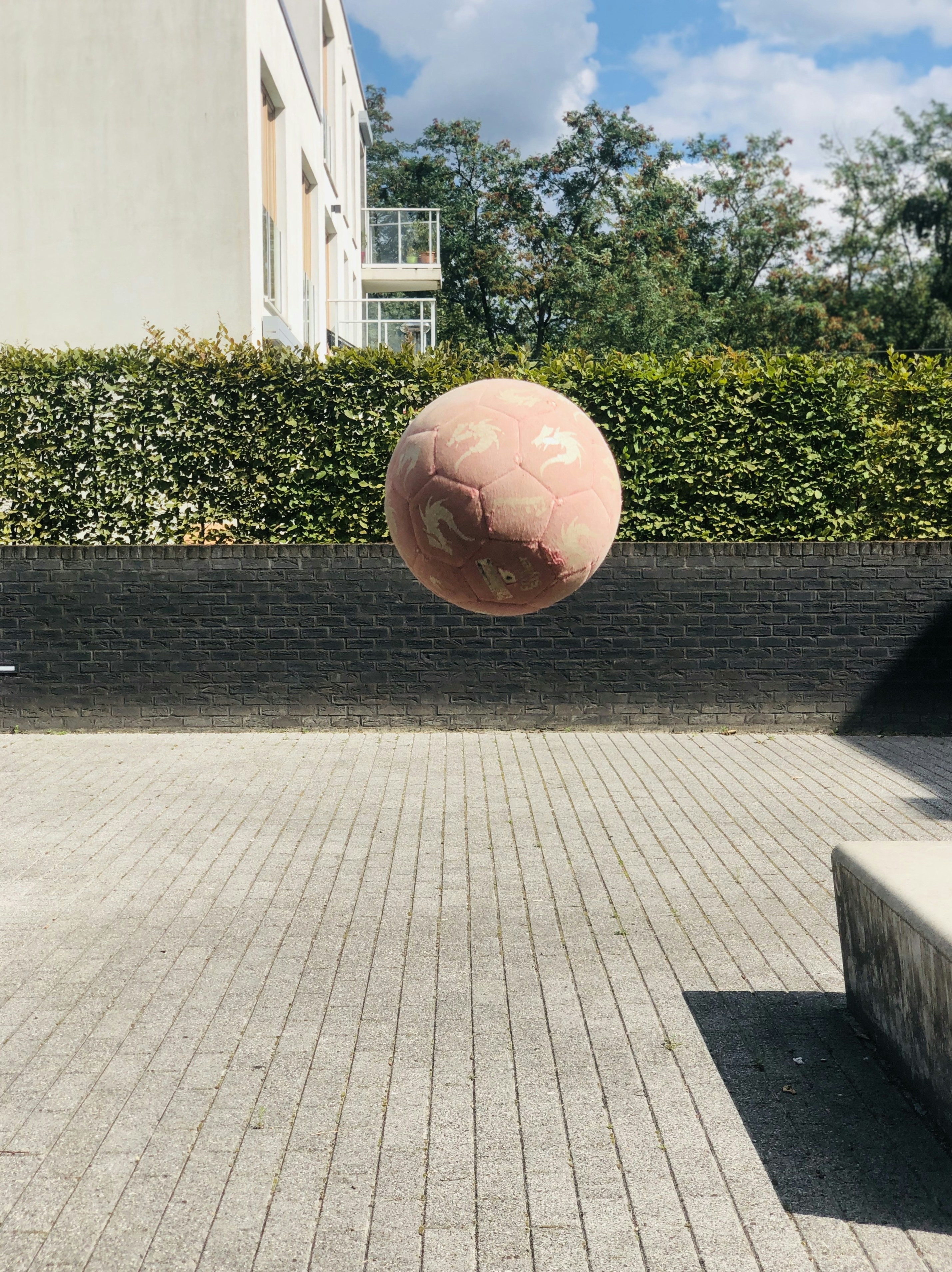 a pink ball is in the air over a brick walkway