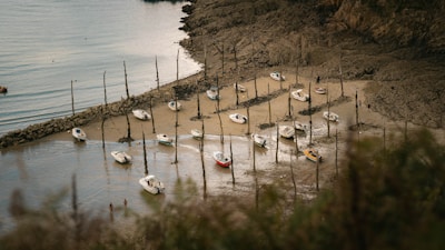 A calm coastal cove with several boats anchored, waiting for water supply.