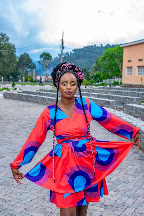 A model wearing a colorful, flowing dress inspired by African heritage, standing against a bright Maltese street backdrop.