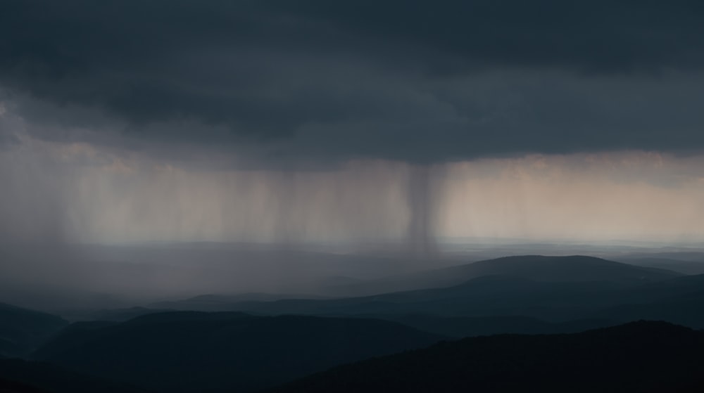 a storm moving through the sky over a mountain range