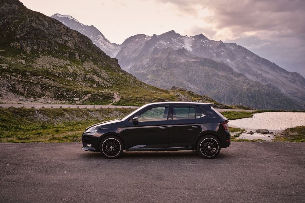 a small black car parked in front of a mountain