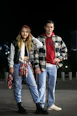 A stylish man and woman showcasing modern ready-to-wear clothing in a cozy urban setting.