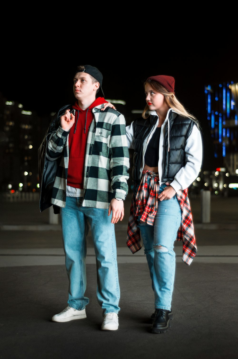 a man and a woman walking down a street at night