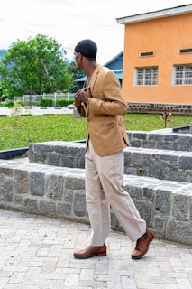 A model walking down a sunlit street wearing a tailored beige blazer paired with chic trousers.