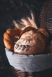 A rustic basket filled with various artisan breads, set against a backdrop of warm brown textures.