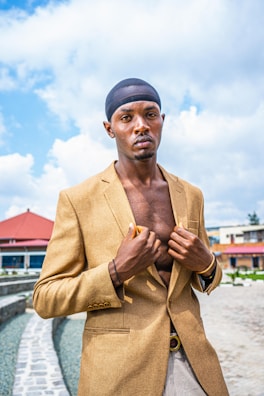 A stylish man in a tailored African print blazer standing confidently on a city street.