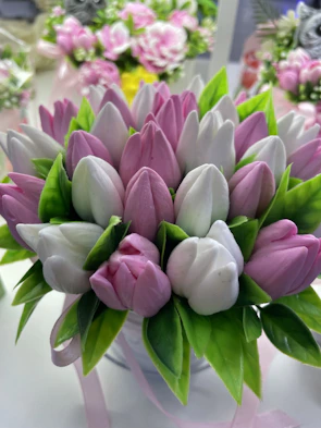 A luxurious box floral arrangement featuring soft pastel tulips and lush greenery accented with golden ribbons.